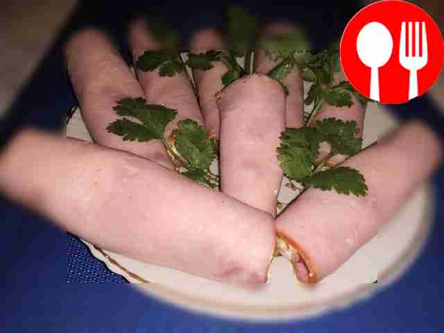 Разложите на тарелке рулеты из ветчины,...