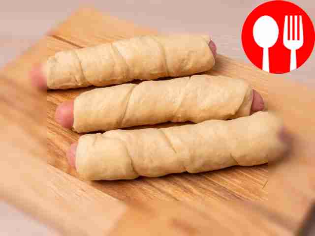 Заверните каждую сосиску в полоску теста.