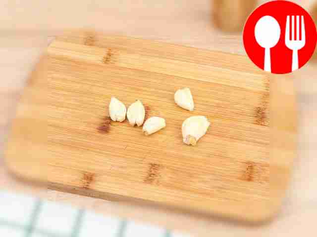 Раздавите зубчик чеснока плоской стороной ножа.